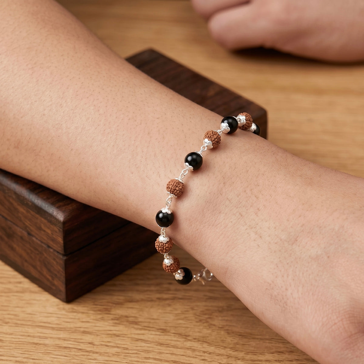 Close up of wrist wearing Karungali and rudraksh bracelet made in pure 925 sterllng silver by silveristhan