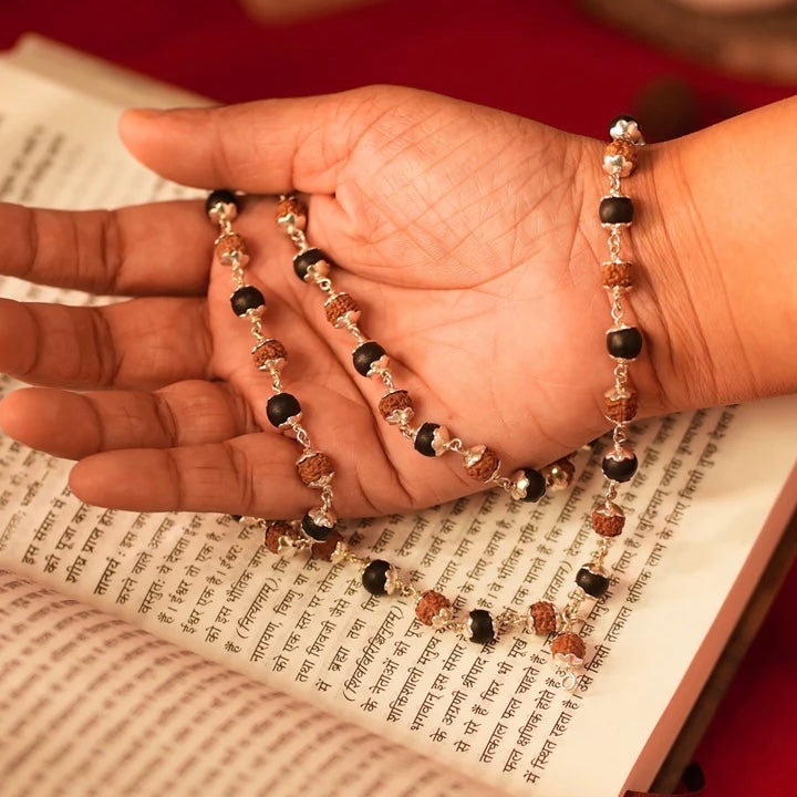 Close up image of hand showcasing a karungali and rudraksha mala made in pure 925 sterling silver by silveristhan
