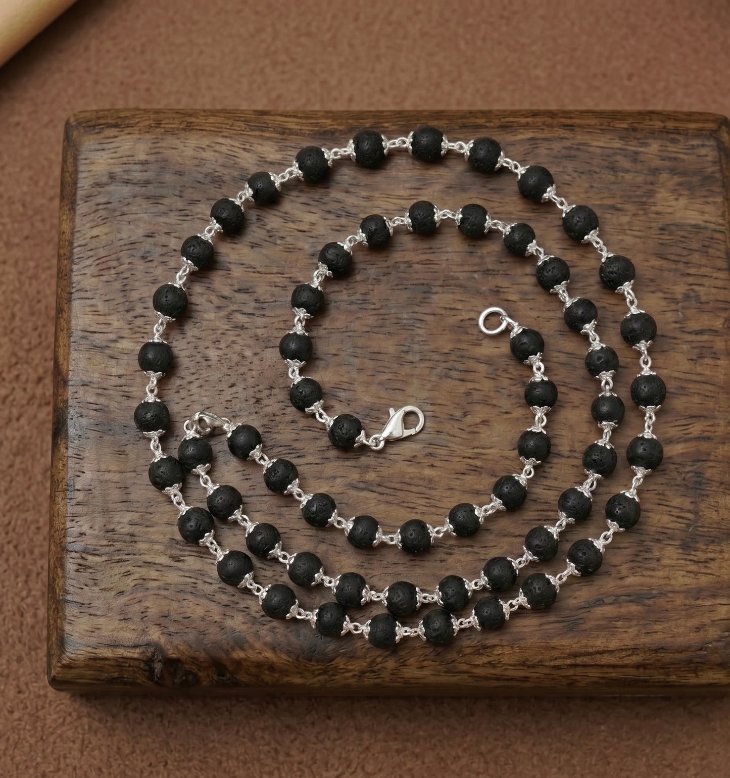 Karungali beads mala made in pure 925 sterling silver on a dark wooden surface