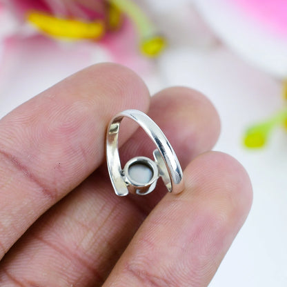 Back size of a silver ring with pearl shown in a person hand on a white blurred back ground.
