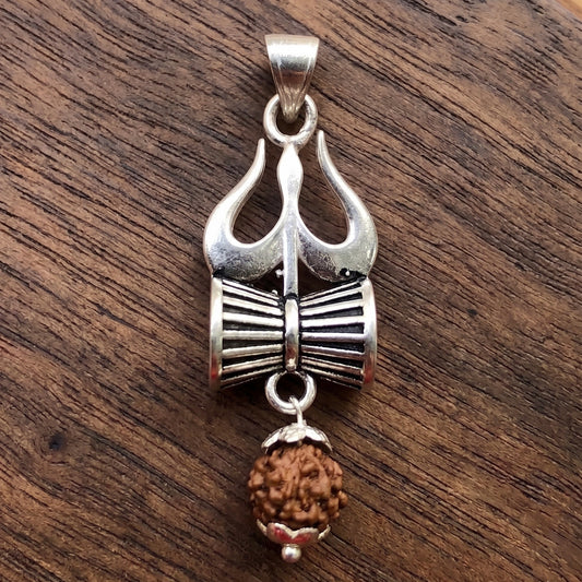 Close Up image of Silver Trishul Damru pendant with hanging panchmukhi rudraksh on a dark wooden surface by silveristhan
