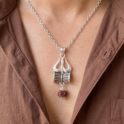 Close up image of a person neck wearing a silver trishul damru pendant with hanging panchmukhi rudraksh pendant by silveristhan