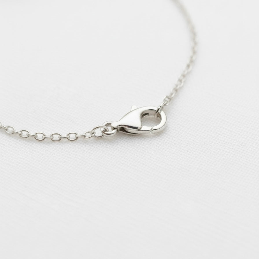Close-up of a silver clasp  on a Silver Om chain Bracelet against a white background