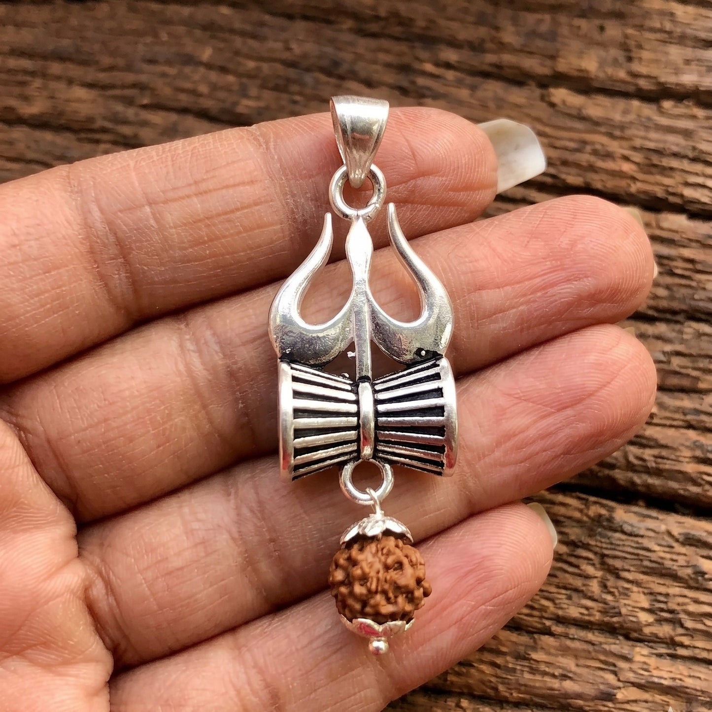Close Up Image of Person Hand showing a Trishul Damru pendant with hanging Panchmukhi Rudraksha made in 925 sterling silver by Silveristhan